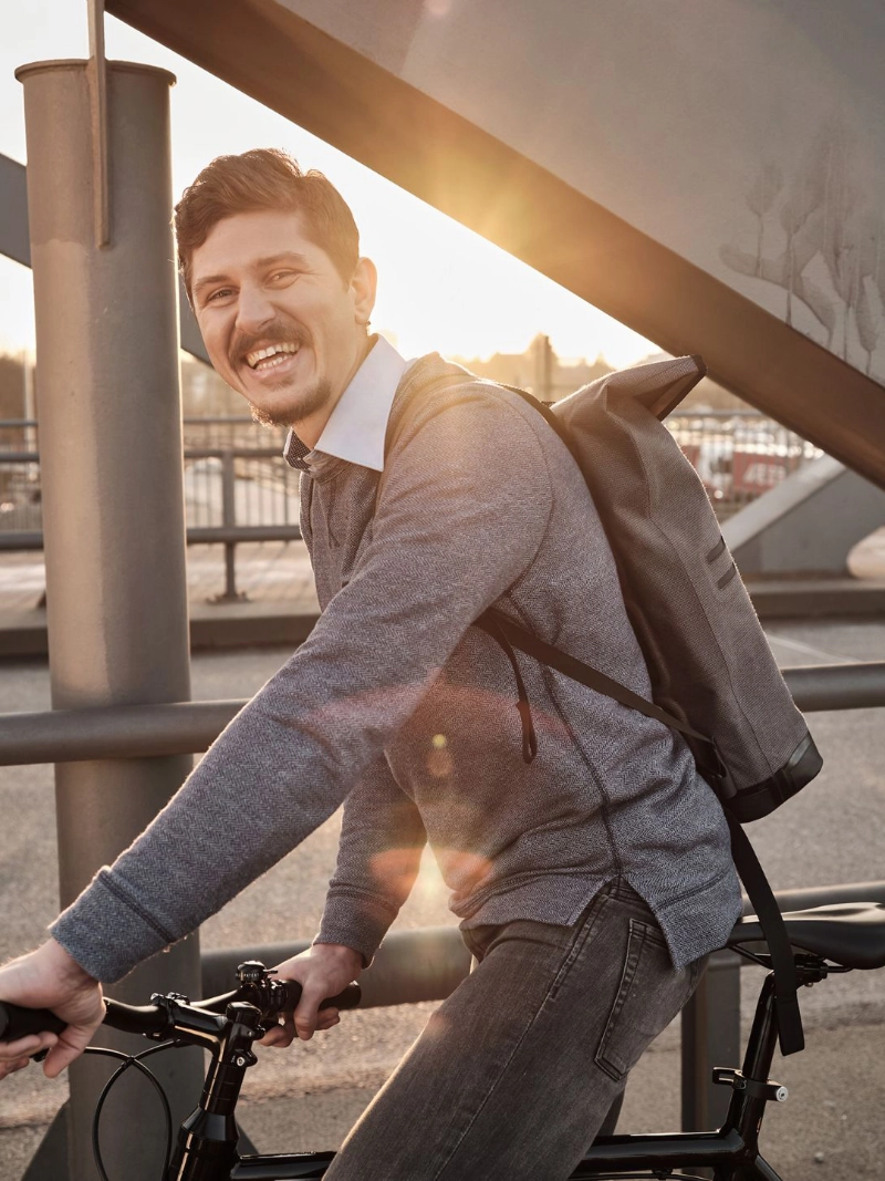 Ein lachender JobRadler fährt im Sonnenuntergang über eine Brücke
